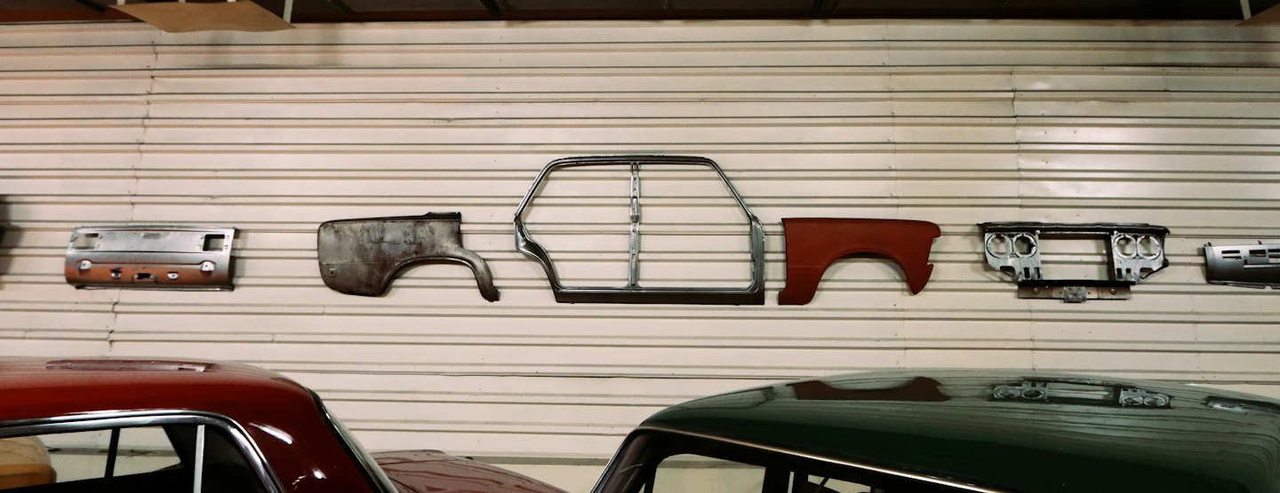 Vintage car parts displayed on a corrugated metal wall in a garage.