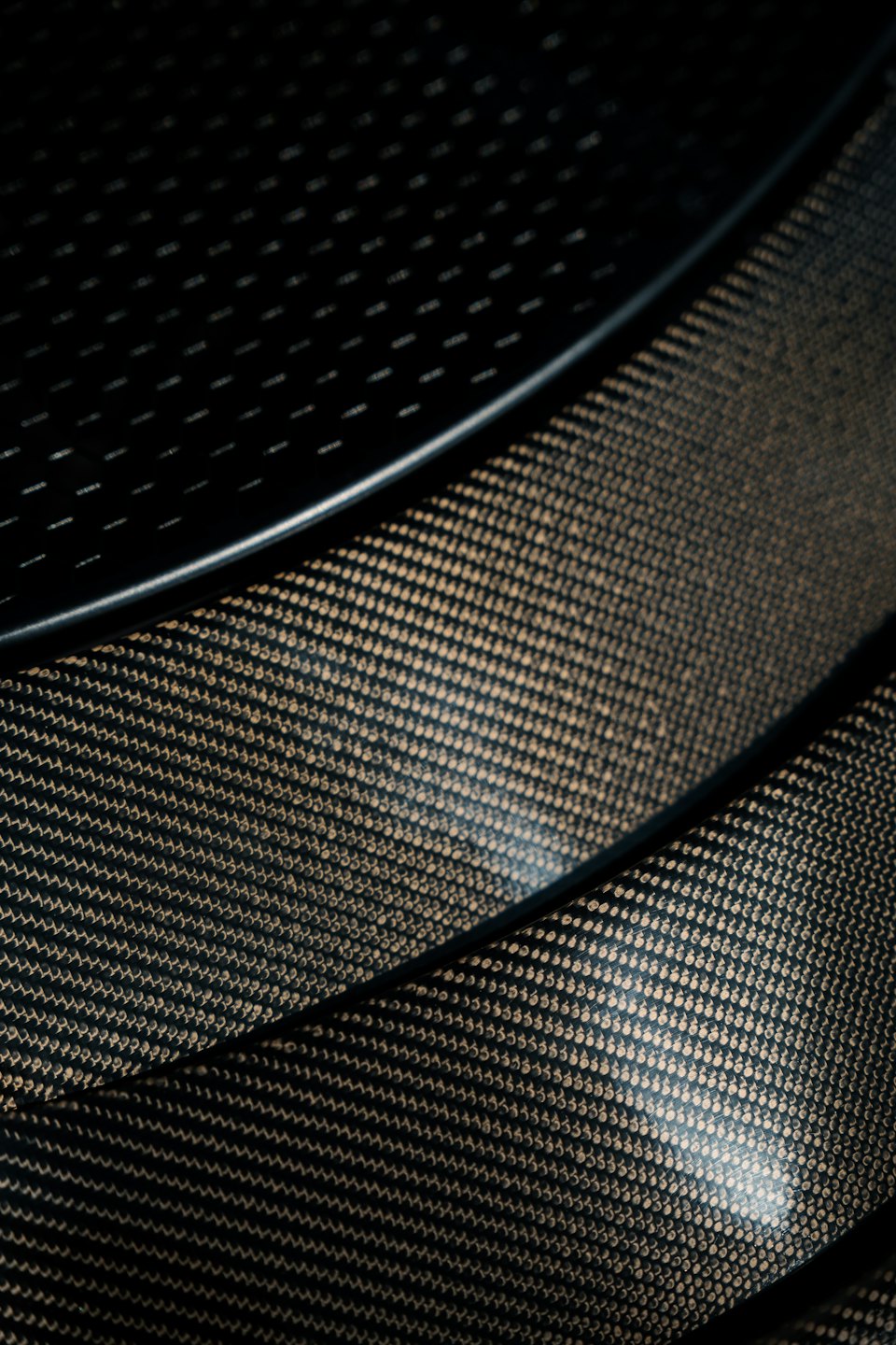 Intricate woven patterns on a dark carbon fiber surface.